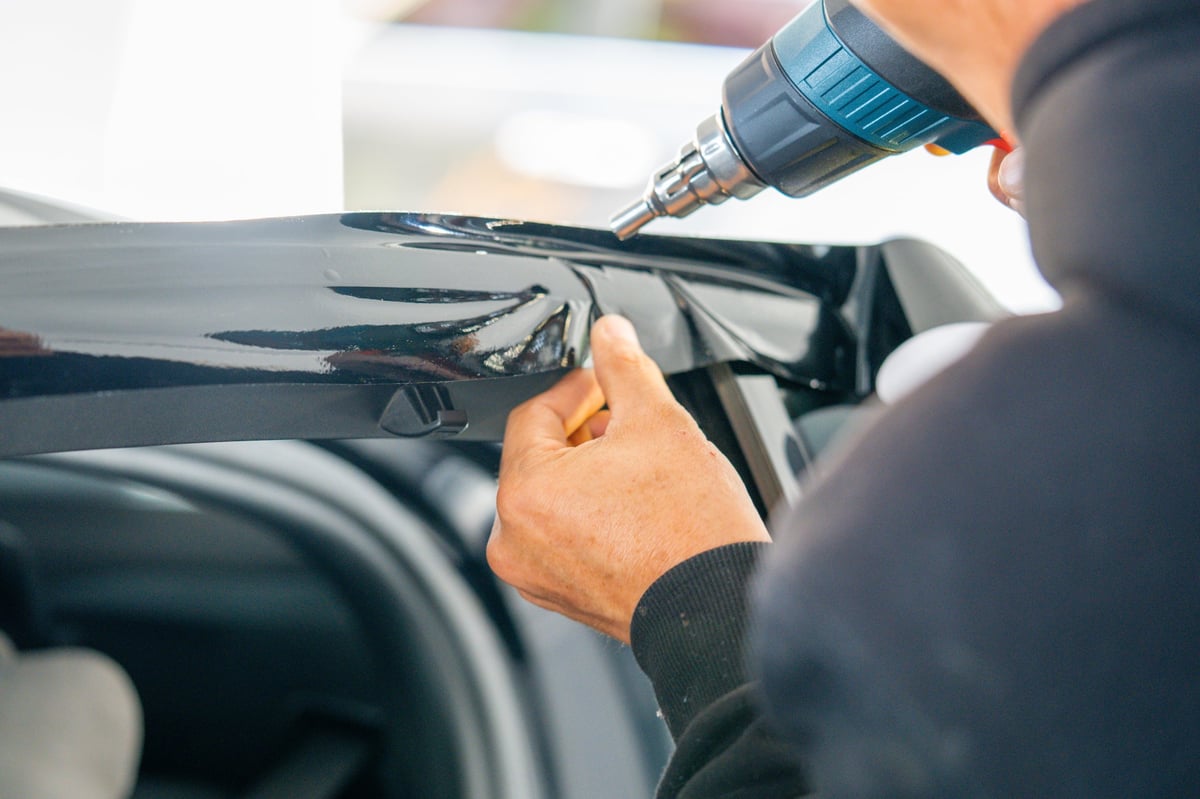 A car wrapping specialist applies a polyurethane film to the car. Detailer smoothes PPF. Car wrapping, detailing, tuning and styling.