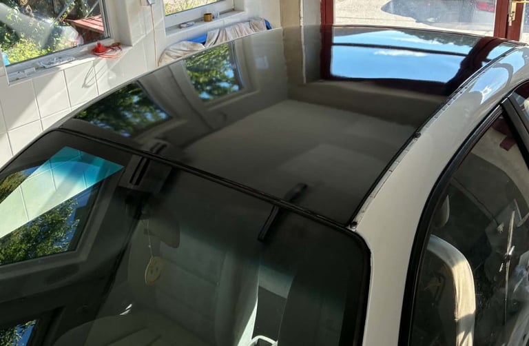 Black roof rack with crossbars installed on white car parked outdoors near house